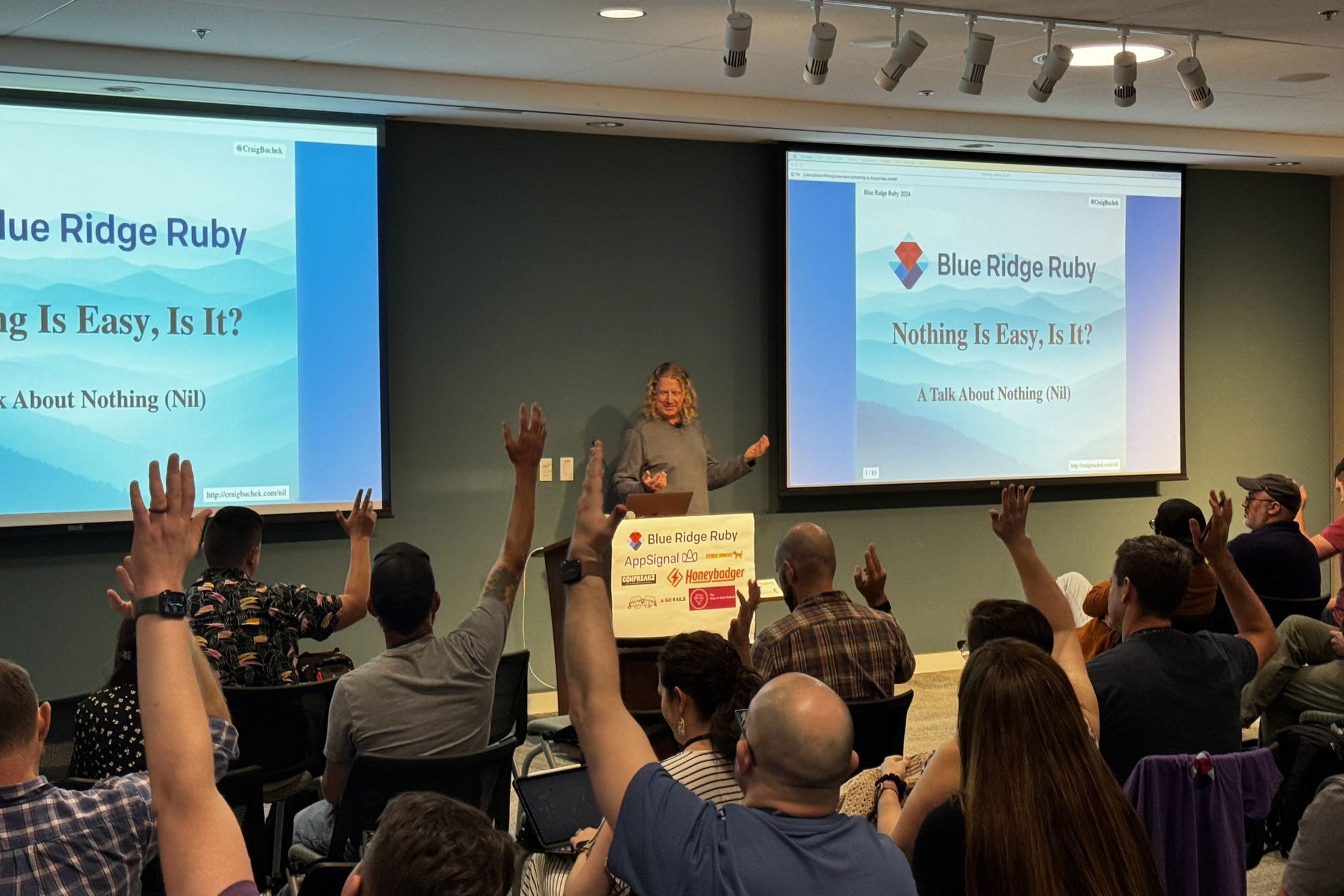 Speaker engaging with the audience during a presentation titled “Nothing Is Easy, Is It? A Talk About Nothing (Nil)” at the Blue Ridge Ruby conference, with several attendees raising their hands in response.