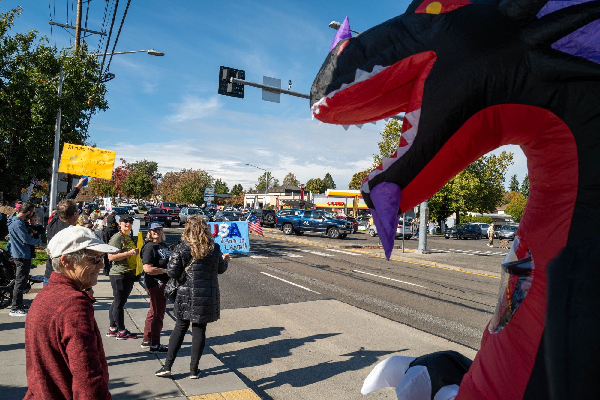 A group of protesters with a person in an inflatable dragon costume in the foreground 