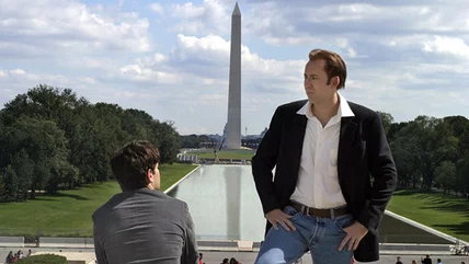 Nicolas Cage standing in front of the Lincoln Memorial Reflecting Pool, which is reflecting the Washington Monument